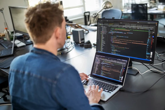 Person sitting in front of a Laptop with another screen above it coding in an IDE