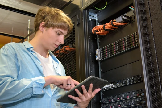 Person standing in front of a serverrack working on a tablet